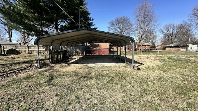 view of yard with a detached carport, driveway, and fence