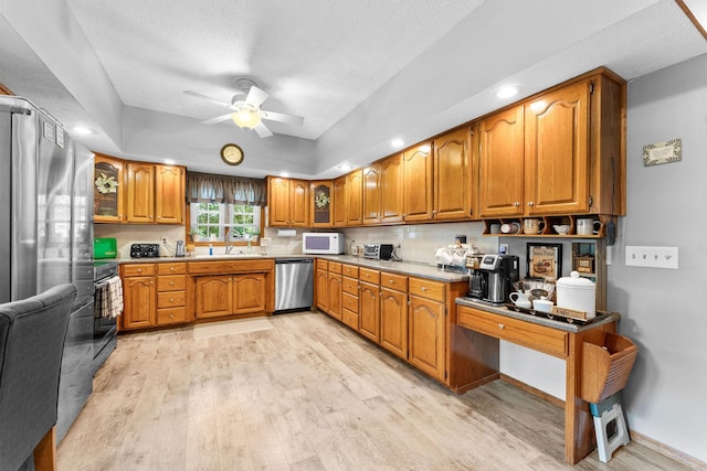 kitchen with brown cabinets, stainless steel appliances, a ceiling fan, and a sink