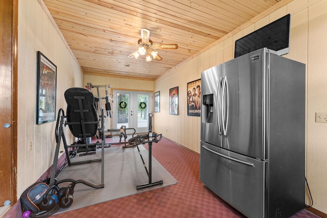 exercise area with a ceiling fan, french doors, carpet floors, wooden ceiling, and wood walls