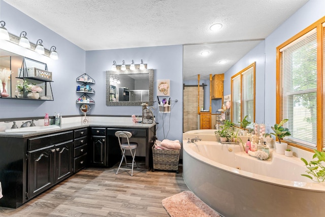 full bath featuring a garden tub, a textured ceiling, wood finished floors, walk in shower, and vanity