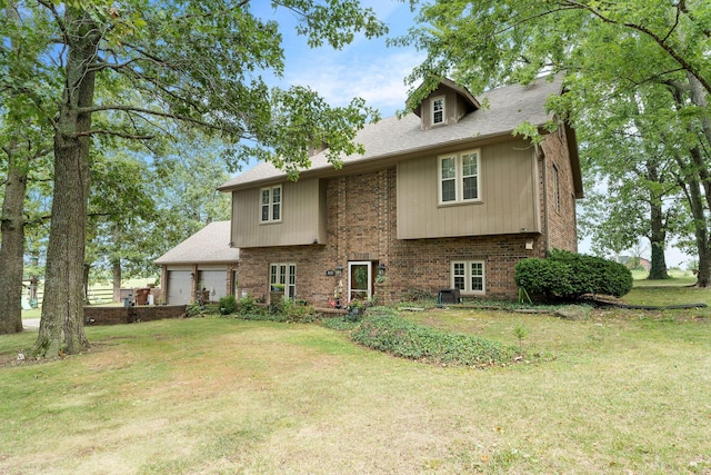 rear view of house featuring a yard, brick siding, and a garage