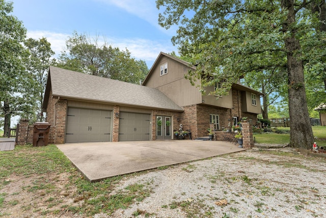 view of front of home featuring french doors, roof with shingles, concrete driveway, an attached garage, and brick siding