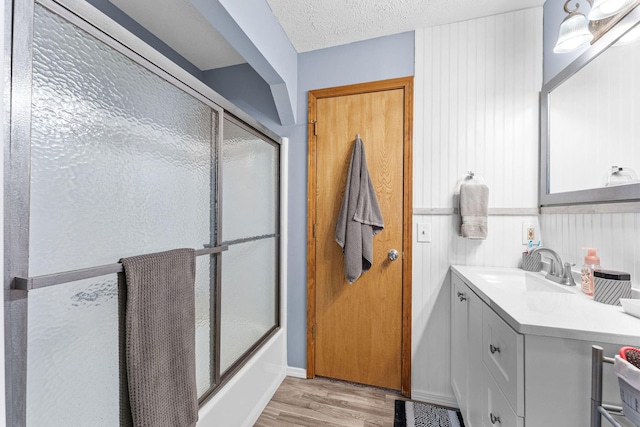 bathroom with enclosed tub / shower combo, a textured ceiling, wood finished floors, and vanity