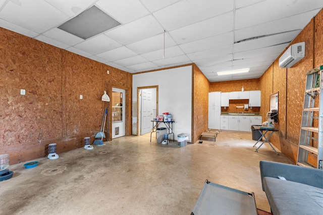 interior space with a paneled ceiling, concrete floors, and a wall mounted AC