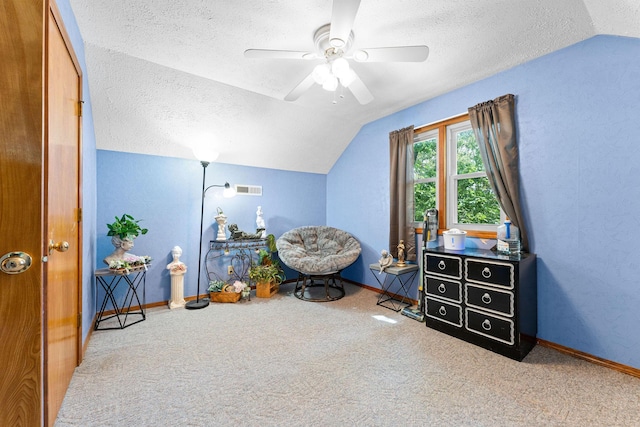 sitting room featuring visible vents, carpet floors, vaulted ceiling, a textured ceiling, and a ceiling fan