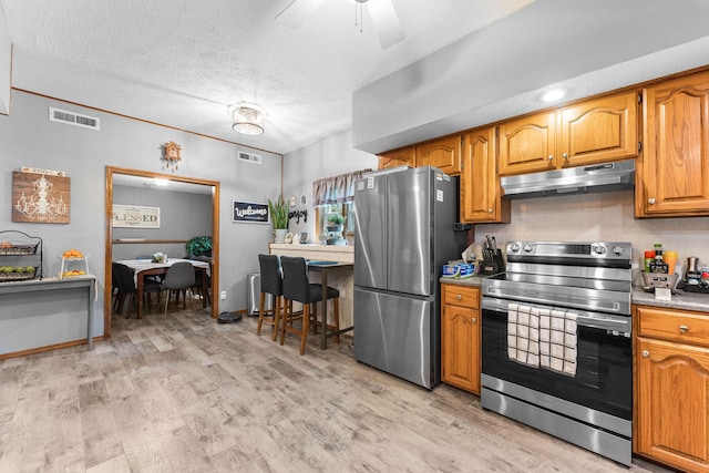 kitchen featuring visible vents, under cabinet range hood, appliances with stainless steel finishes, brown cabinetry, and ceiling fan