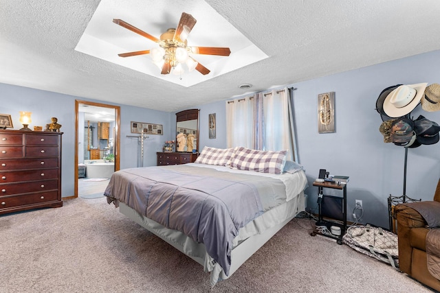 bedroom with connected bathroom, light colored carpet, a ceiling fan, and a textured ceiling