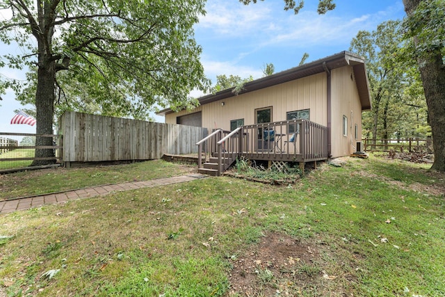 rear view of house with a yard, a wooden deck, and a fenced backyard