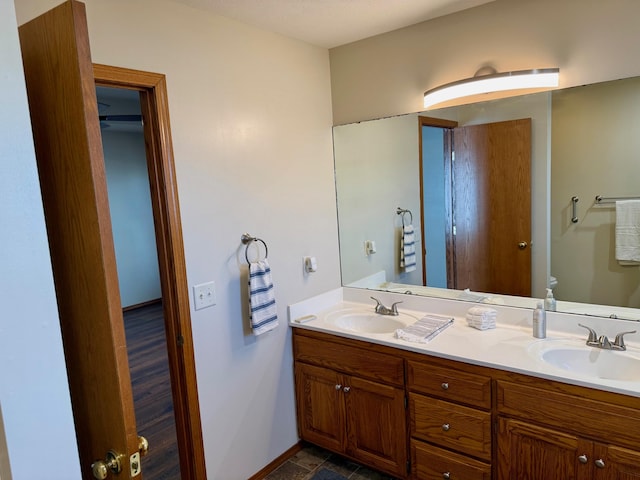 bathroom featuring double vanity, toilet, baseboards, and a sink