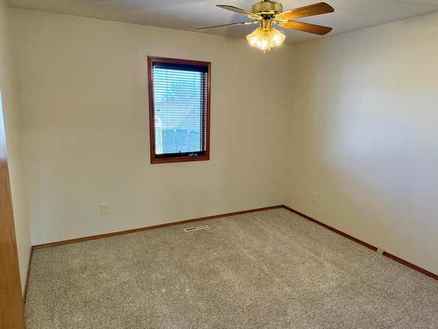 carpeted empty room featuring visible vents, a ceiling fan, and baseboards