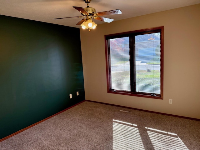 carpeted spare room featuring baseboards and ceiling fan