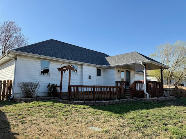 back of house featuring a yard, fence, covered porch, and a shingled roof