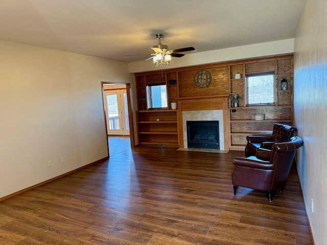 living room featuring baseboards, a fireplace with flush hearth, dark wood-style floors, and a ceiling fan