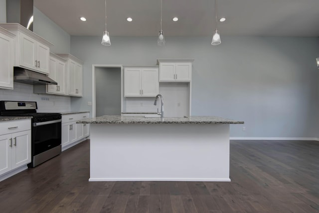 kitchen with under cabinet range hood, a sink, tasteful backsplash, gas stove, and white cabinets