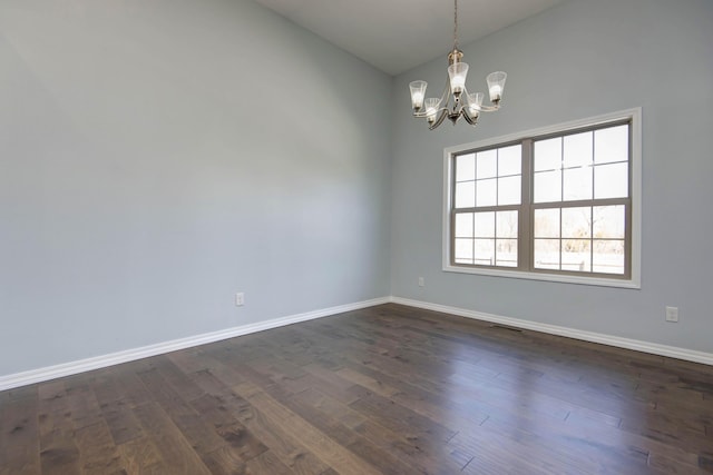 empty room featuring a chandelier, dark wood-style floors, baseboards, and vaulted ceiling