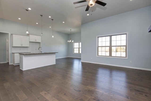 kitchen featuring a kitchen island with sink, ceiling fan with notable chandelier, open floor plan, dark wood-style floors, and white cabinets