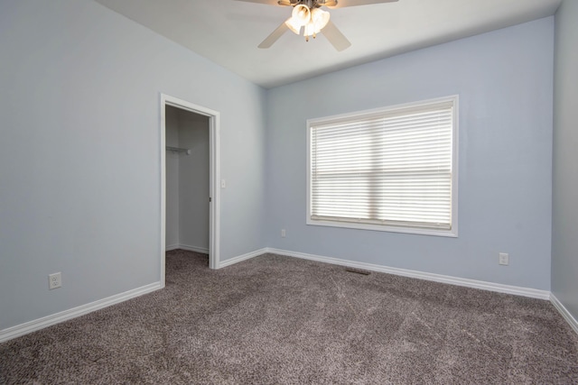 unfurnished bedroom featuring a walk in closet, baseboards, carpet floors, and visible vents