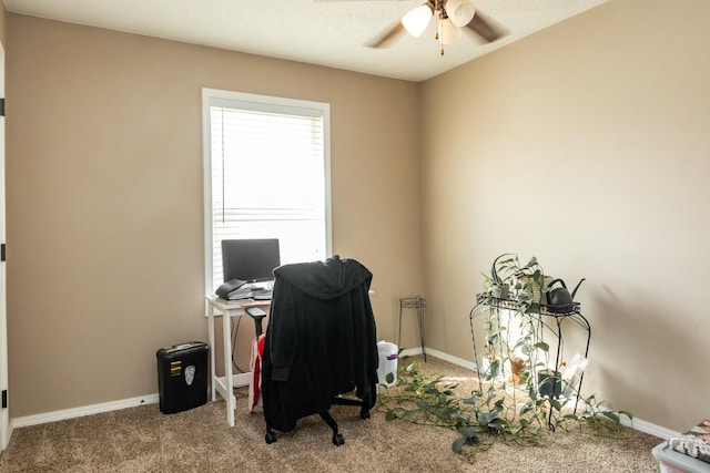 carpeted office space featuring baseboards and ceiling fan