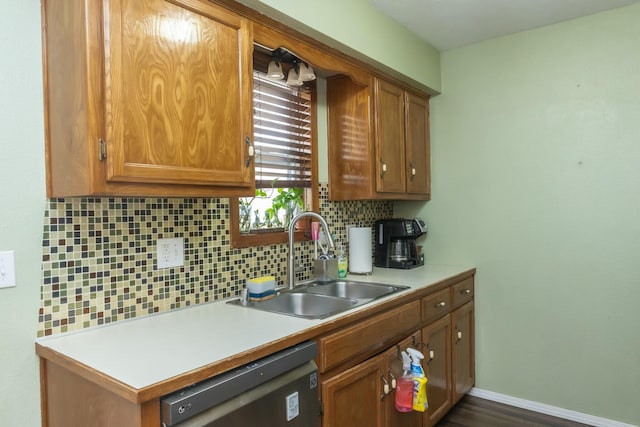 kitchen with brown cabinetry, a sink, decorative backsplash, light countertops, and stainless steel dishwasher