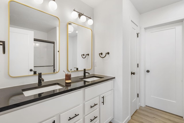 bathroom featuring double vanity, wood finished floors, and a sink