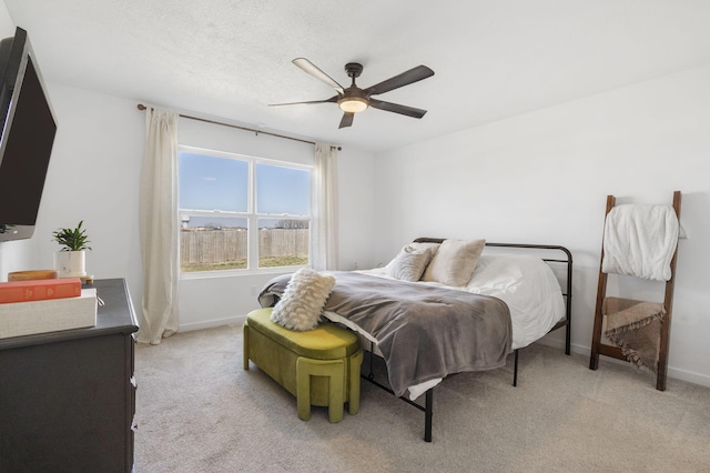 bedroom with light colored carpet, baseboards, and ceiling fan