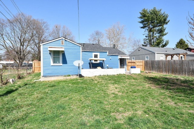 back of property with a lawn, roof with shingles, and a fenced backyard