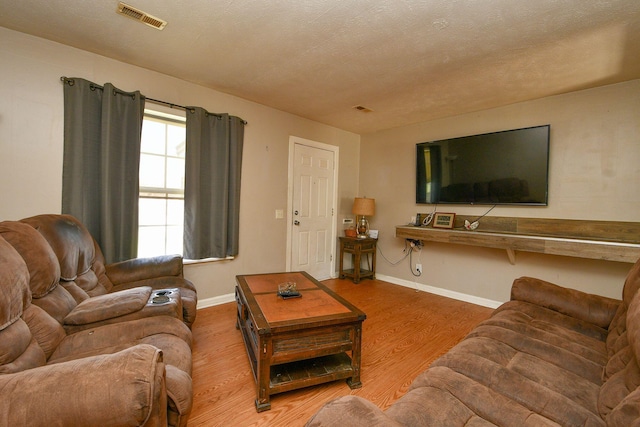 living area with visible vents, baseboards, a textured ceiling, and wood finished floors