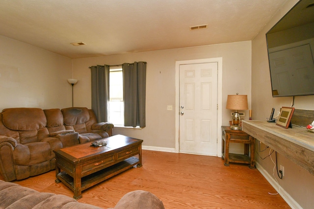 living area featuring visible vents, baseboards, and light wood-style floors