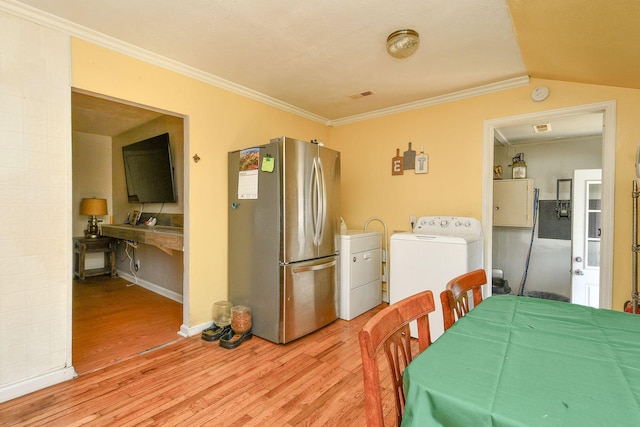 dining room featuring washer / dryer, crown molding, light wood-style flooring, and lofted ceiling