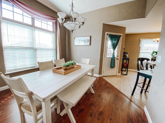 dining room featuring a notable chandelier, plenty of natural light, and a textured wall