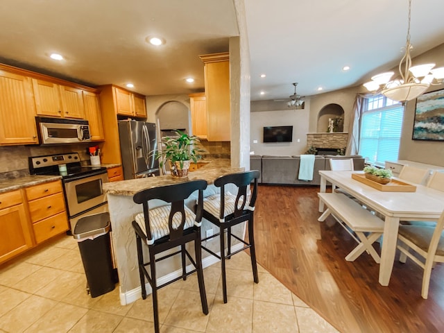 kitchen featuring tasteful backsplash, light tile patterned floors, recessed lighting, appliances with stainless steel finishes, and a notable chandelier