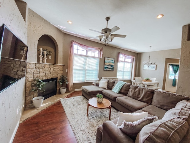 living area featuring wood finished floors, a ceiling fan, baseboards, a fireplace, and recessed lighting