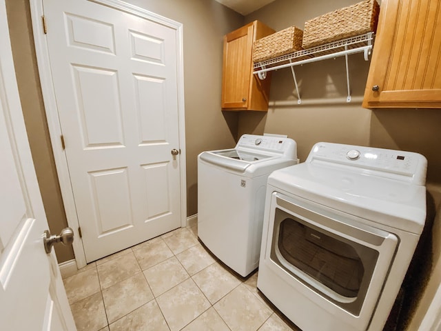 laundry room with washer and dryer, light tile patterned floors, and cabinet space