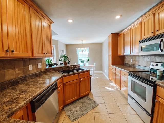 kitchen featuring a notable chandelier, a sink, dark countertops, appliances with stainless steel finishes, and light tile patterned floors