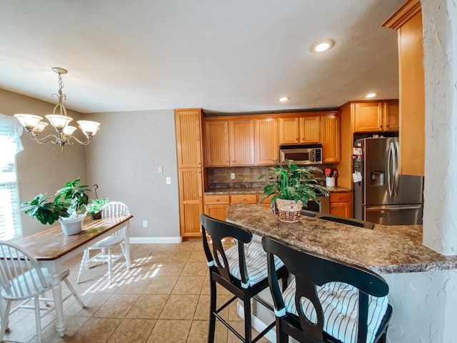 kitchen featuring a chandelier, a breakfast bar, light tile patterned floors, appliances with stainless steel finishes, and a peninsula