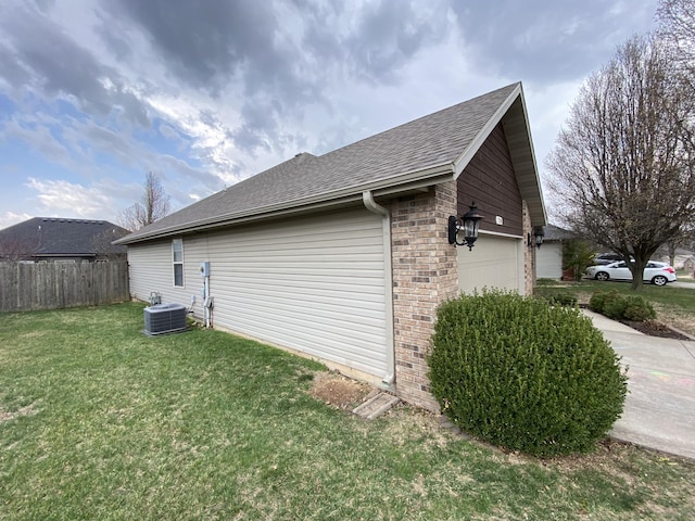 view of side of property featuring a lawn, central AC, fence, an attached garage, and brick siding