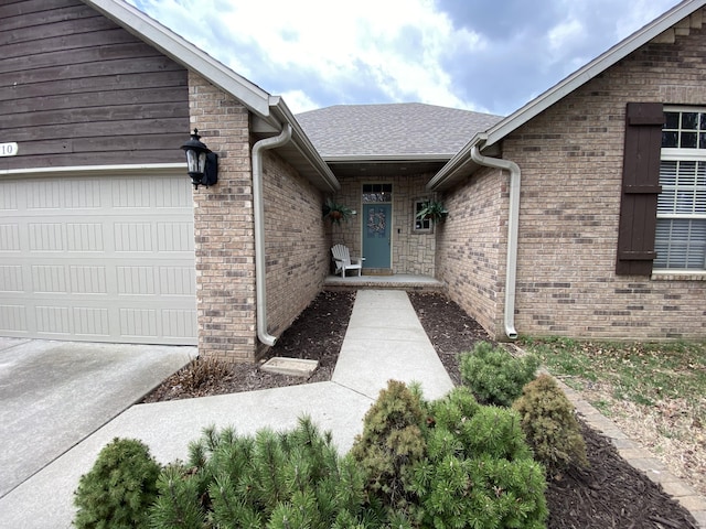 doorway to property featuring brick siding, an attached garage, and a shingled roof