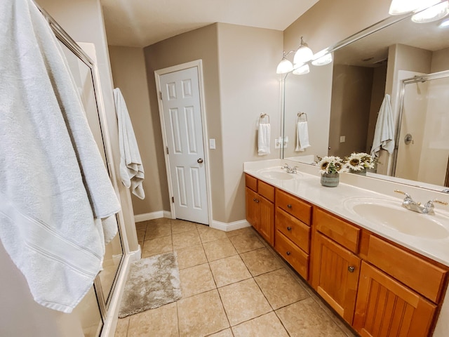 full bath featuring a sink, a stall shower, double vanity, and tile patterned flooring