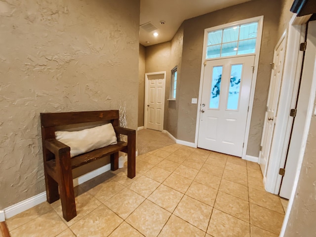 entrance foyer with light tile patterned flooring, baseboards, and a textured wall