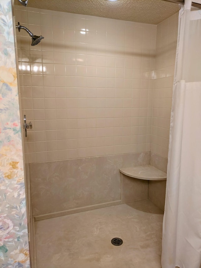 bathroom with a textured ceiling and a tile shower