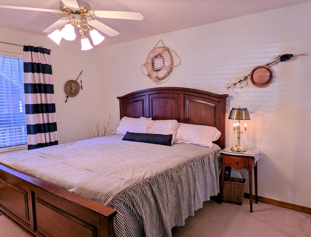 bedroom with light carpet, baseboards, a textured ceiling, and a ceiling fan