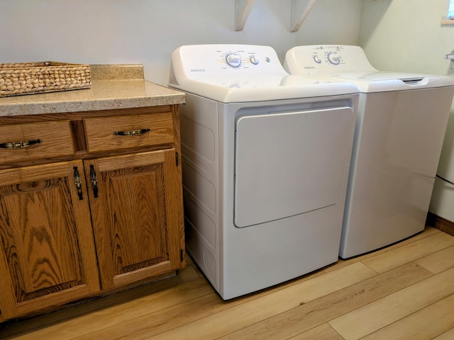 washroom with washer and dryer, cabinet space, and light wood finished floors