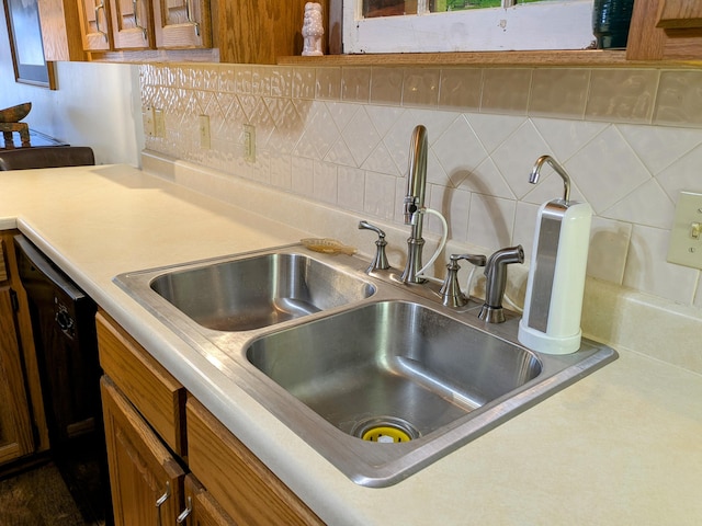 kitchen featuring a sink, brown cabinetry, light countertops, decorative backsplash, and dishwasher