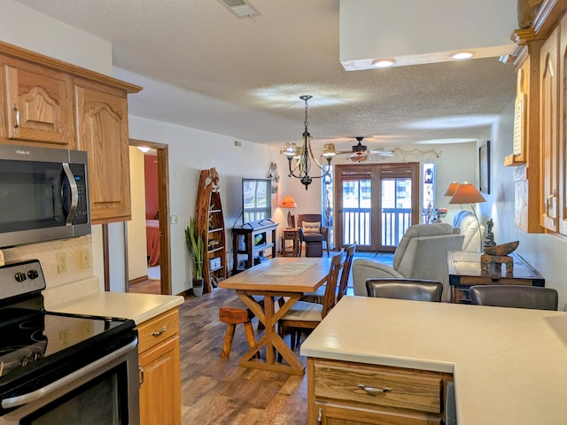 kitchen featuring open floor plan, light countertops, dark wood-style floors, stainless steel appliances, and a ceiling fan