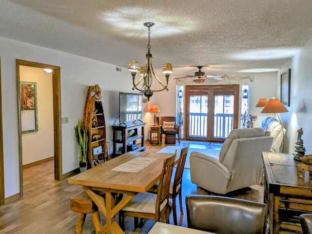 dining room featuring baseboards, ceiling fan with notable chandelier, a textured ceiling, and light wood-style floors