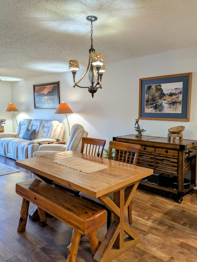 dining area featuring wood finished floors, a textured ceiling, and a chandelier