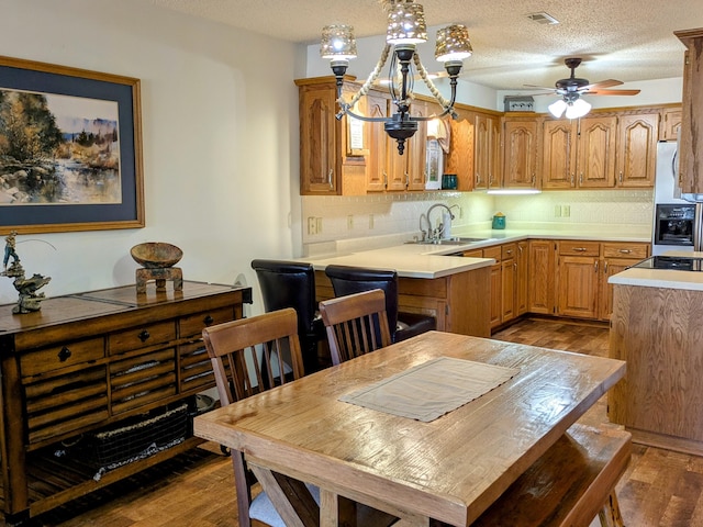 kitchen featuring visible vents, backsplash, wood finished floors, a textured ceiling, and a sink