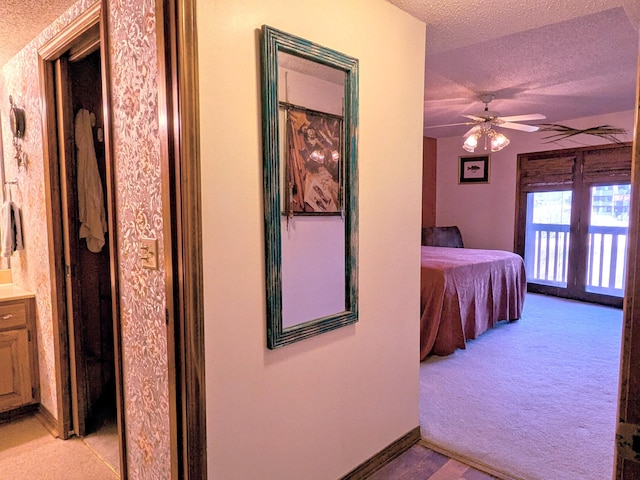 unfurnished bedroom featuring baseboards, light colored carpet, a textured ceiling, a ceiling fan, and access to outside