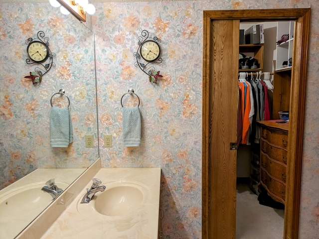 bathroom featuring vanity, wallpapered walls, and a walk in closet