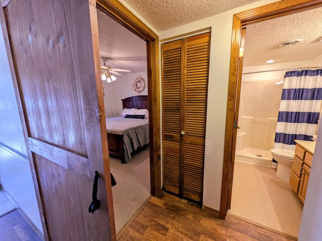 hallway featuring wood finished floors, visible vents, and a textured ceiling